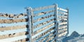 Fence near mountain slope covered by heavy snow on a sunny winter day Royalty Free Stock Photo