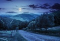 Fence near road down the hill with forest in mountains at night Royalty Free Stock Photo