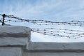 Fence with old barbed wire. Barbed wire against the blue sky. Rusty barbed wire.