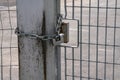 Fence: pole and padlock with chain to a fence with electro-welded metal grid in stainless steel. Royalty Free Stock Photo