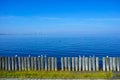 Timber groins at the calm sea by blue sky, coastal landscape with wind park