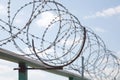 Fence with razor barbed wire protection against blue sky background. Dictatorship and tyranny concept