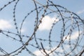 Fence with razor barbed wire protection against blue sky background. Dictatorship and tyranny concept