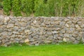 Fence real stone wall surface with cement on green grass field