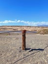 Fence of round wooden posts attached with a rope to delimit the path.Wooden post in desert landscape with lagoon and blue sky. Royalty Free Stock Photo