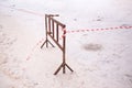 Fence with a signal white-red tape marking dangerous icy pavement.