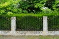 Fence with stone columns,  green grass and trees Royalty Free Stock Photo