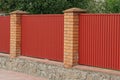 fence on the street of brown bricks and red metal