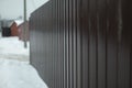 Fence in winter. Solid fence made of prof sheet. Steel brown prof sheet Royalty Free Stock Photo