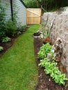 Fenced in garden with stone block wall and gate in late summer Royalty Free Stock Photo