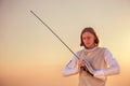 Fencer man holding his sword in both hands looking down on sunset background Royalty Free Stock Photo