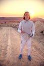 Fencer man wearing white fencing costume holding sword and looking forward