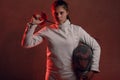 Fencer woman with fencing epee sword on shoulder in red light