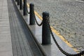 Fencing of sidewalk in form of black cast iron posts with iron chains