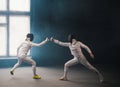 A fencing training in the studio - two women in protective costumes having a duel - poking with a swords in each other