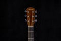 Fender acoustic guitar head with tuning pegs and fretboard on isolated black background