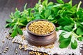 Fenugreek in bowl with leaves on board Royalty Free Stock Photo