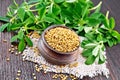 Fenugreek in bowl with leaves on dark board Royalty Free Stock Photo