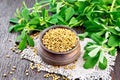 Fenugreek in bowl with leaves on dark wooden board Royalty Free Stock Photo