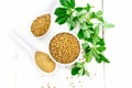 Fenugreek in bowl and two spoons with leaves on board top Royalty Free Stock Photo