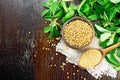 Fenugreek in spoon and bowl with green leaves on dark board top Royalty Free Stock Photo