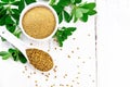 Fenugreek in spoon and bowl with leaves on board top Royalty Free Stock Photo