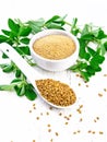 Fenugreek in spoon and bowl with leaves on white wooden board Royalty Free Stock Photo