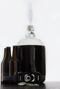 Fermented beer in a demijohn with airlock and hand capper with dark brown bottles and caps Royalty Free Stock Photo