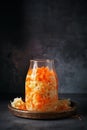 Fermented cabbage and carrots preserved in a glass jar, on dark kitchen countertop. Sauerkraut. Generative AI