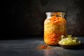 Fermented cabbage and carrots preserved in a glass jar, with spices, on dark kitchen countertop. Generative AI