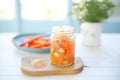 fermented carrots and ginger in a clear glass jar on a white wooden table