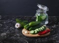 Fermented cucumbers in a glass jar, freshly chopped cucumbers, hot peppers, garlic, dill on a black background Royalty Free Stock Photo