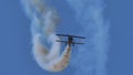 Vintage airplane flies in the blue sky with white smoke