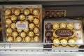 Ferrero Rocher and Raffaello chocolate candy collection in golden packaging on a supermarket shelf.