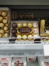 Ferrero Rocher and Raffaello chocolate candy collection in golden packaging on a supermarket shelf.