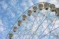 Ferris wheel detail low-angle by blue sky with white fluffy clouds Royalty Free Stock Photo