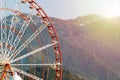 Ferris Wheel Against A Backdrop Of Mountains Covered With Forests.