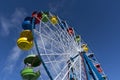 Ferris Wheel With Colored Cabins On The Blue Sky Background, Sun