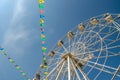 Ferris wheel and colorful flags on blue sky background
