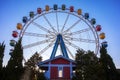 Ferris wheel with colorful swings at sunsets with blue sky in front view