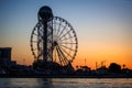 Ferris wheel and Georgian alphabet tower on orange sunset background. Royalty Free Stock Photo