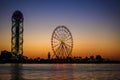 Ferris wheel and Georgian alphabet tower on orange sunset background. Royalty Free Stock Photo