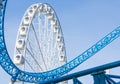Ferris wheel and Loop turn on a blue roller coaster in an amusement park. Royalty Free Stock Photo