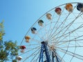 Ferris wheel with multi-colored booths against a clear blue sky. Bottom view. Soviet era amusement ride