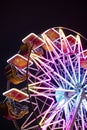 Ferris wheel at night, illuminated by colorful neon lights. Detail, vertical