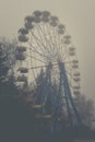 Ferris wheel in an old abandoned park in the autumn in thick fog