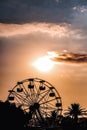 Ferris wheel silhouette on a cloudy sky and sunset colors, summer amusement ride Royalty Free Stock Photo