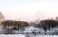 Ferris wheel in winter Park with pond on city background. Pink sunset sky. Royalty Free Stock Photo