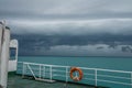 Ferry Boat with Orange Life-Buoy Ring Sail in Bad Weather with Thunderclouds. Marine Safety Concept Royalty Free Stock Photo