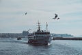 Ferry boat in the water of Bosphorus in Istanbul with the city in the background - seagulls flying around Royalty Free Stock Photo